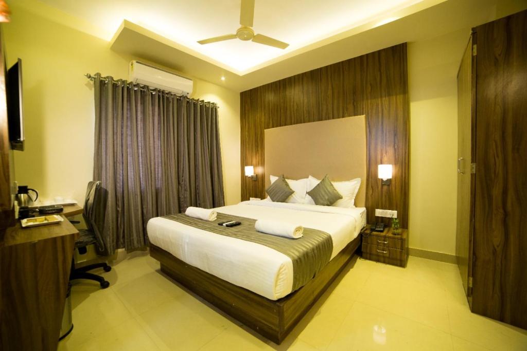 a bedroom with a large bed and a desk at Hotel Plaza Heights in Bangalore