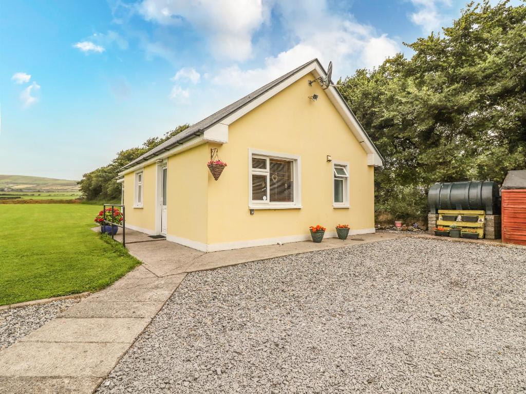 a small yellow house with a gravel driveway at Moybella Lodge in Ballybunion