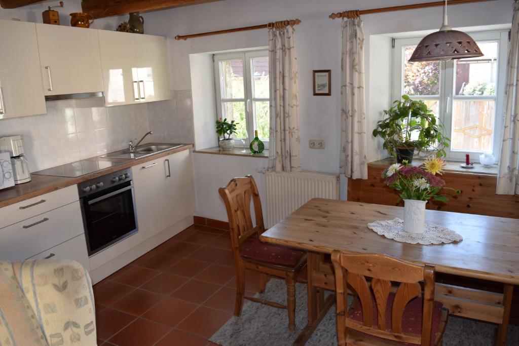 eine Küche mit einem Holztisch sowie einem Tisch und Stühlen in der Unterkunft Apartments Bed & Breakfast Brückner in Willanzheim