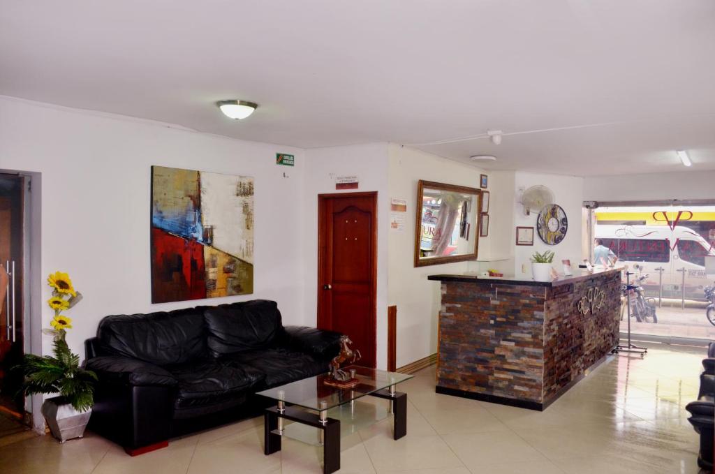 sala de estar con sofá negro y mesa en Hotel Plaza Ventura, en Barranquilla