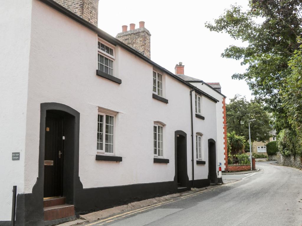 uma casa branca com janelas pretas e uma rua em Cuddfan em Llangollen