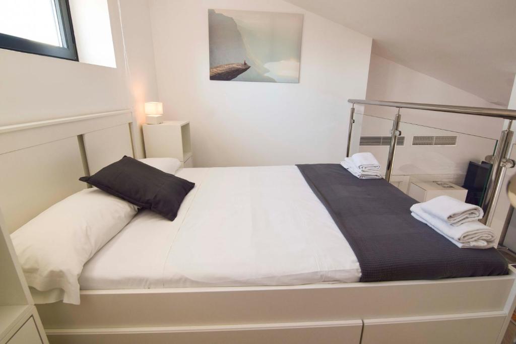 1 dormitorio con 1 cama con sábanas blancas y almohadas negras en Letmalaga Sweet wells, en Málaga