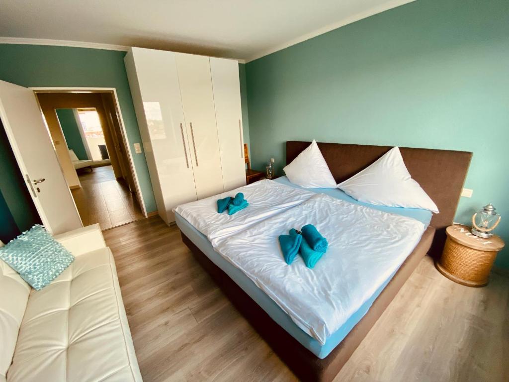 a bedroom with a bed with two blue bows on it at COAST HOUSE Dünenloft in Bremerhaven