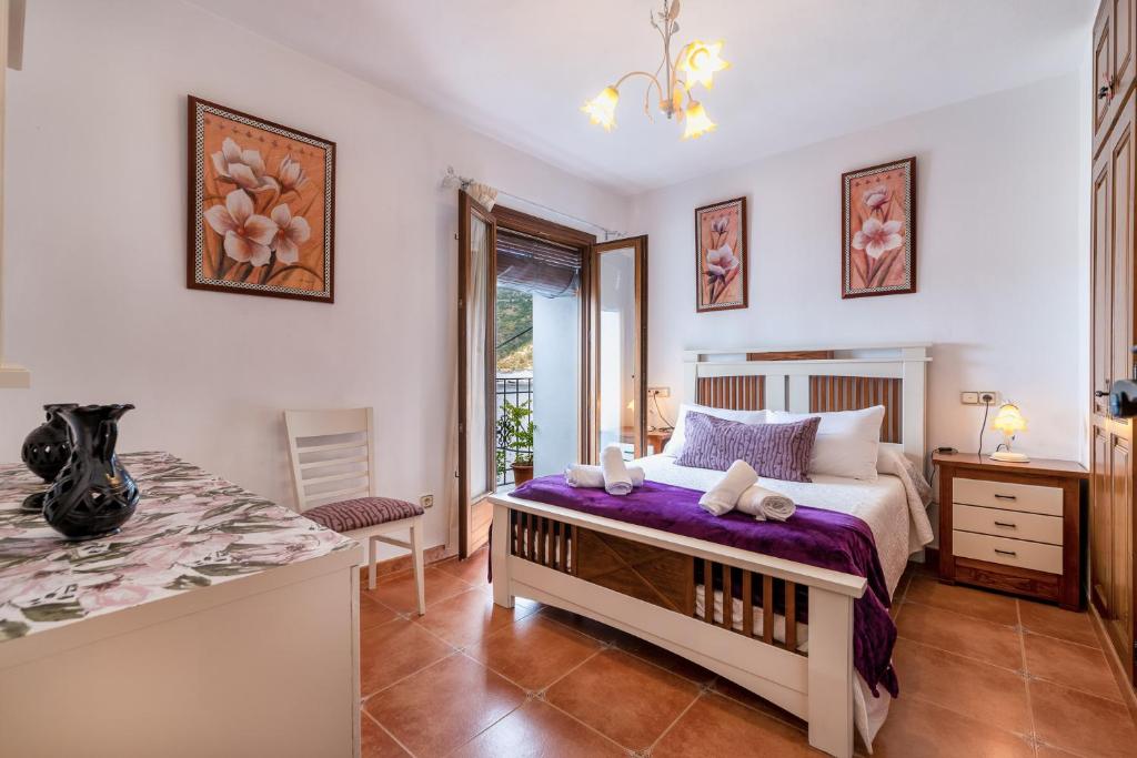 a bedroom with a bed with purple sheets and a table at Casa abuela pilar in Capileira