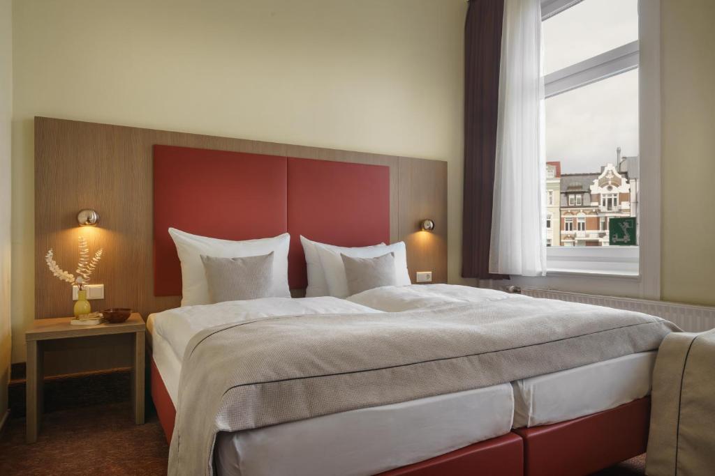 a bedroom with a large bed and a large window at Novum Hotel Norddeutscher Hof Hamburg in Hamburg