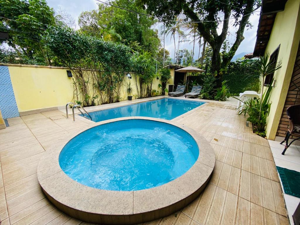 una gran piscina azul en un patio con suelo de madera en ILHABEACH GUESTHOUSE en Ilhabela