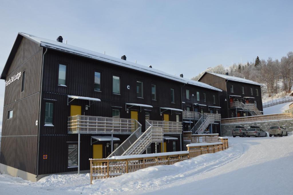 弗納斯達倫的住宿－Ski Lodge Funäsdalen，雪中一座黑色的大建筑,有楼梯
