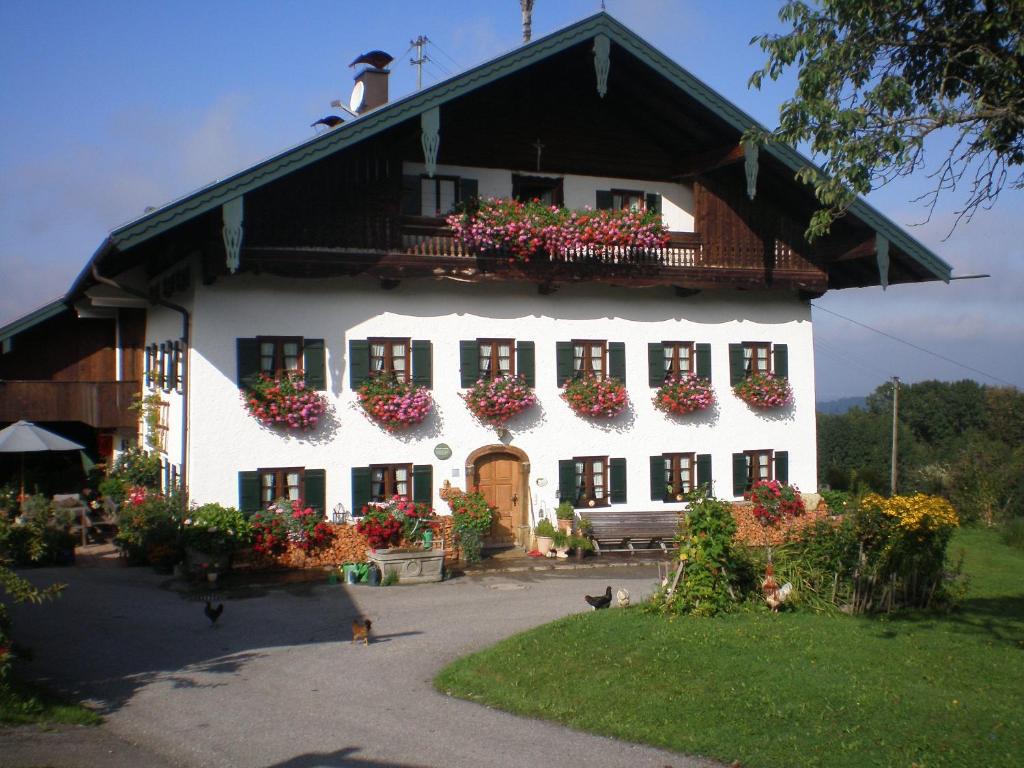 un bâtiment blanc avec des boîtes de fleurs sur les fenêtres dans l'établissement Stadlerhof, à Frasdorf