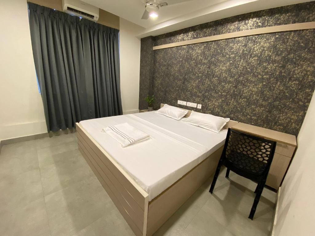 - une chambre avec un lit et une chaise dans l'établissement KARIPPALS INN, à Kottayam