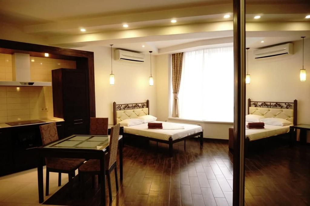 Habitación con 2 camas, mesa y cocina. en Doba In Ua Most-Sity Apartments, en Dnipro