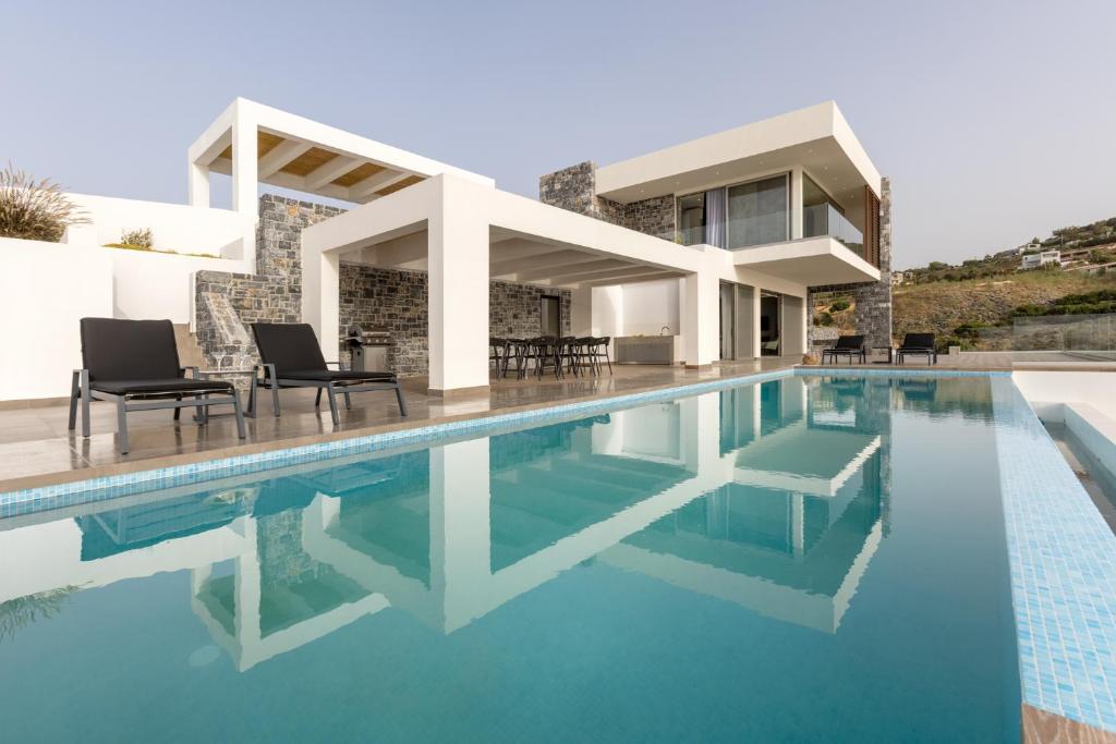 une villa avec une piscine et une maison dans l'établissement Rock Bay Villas - Luxury Villas in Crete, à Agia Pelagia