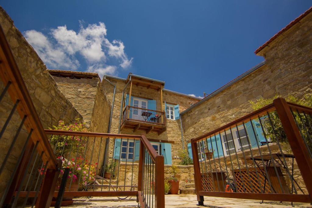 an old stone building with a balcony and stairs at Dolphin Guest House and Studios in Tochni