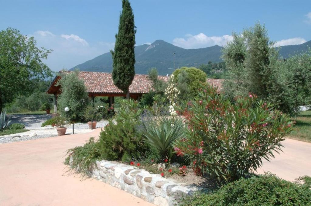 a garden in front of a house with mountains in the background at Agriturismo Renzano garden apartments in Salò