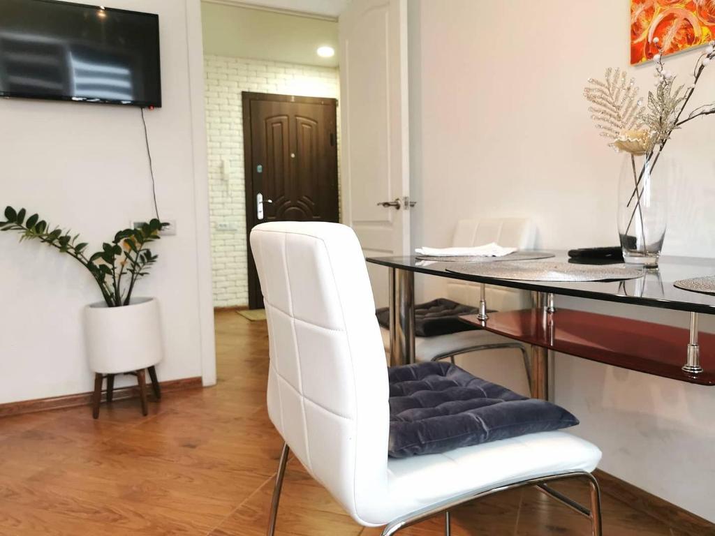 a white dining room with a glass table and white chairs at Studio Apartment in the center in Shostka