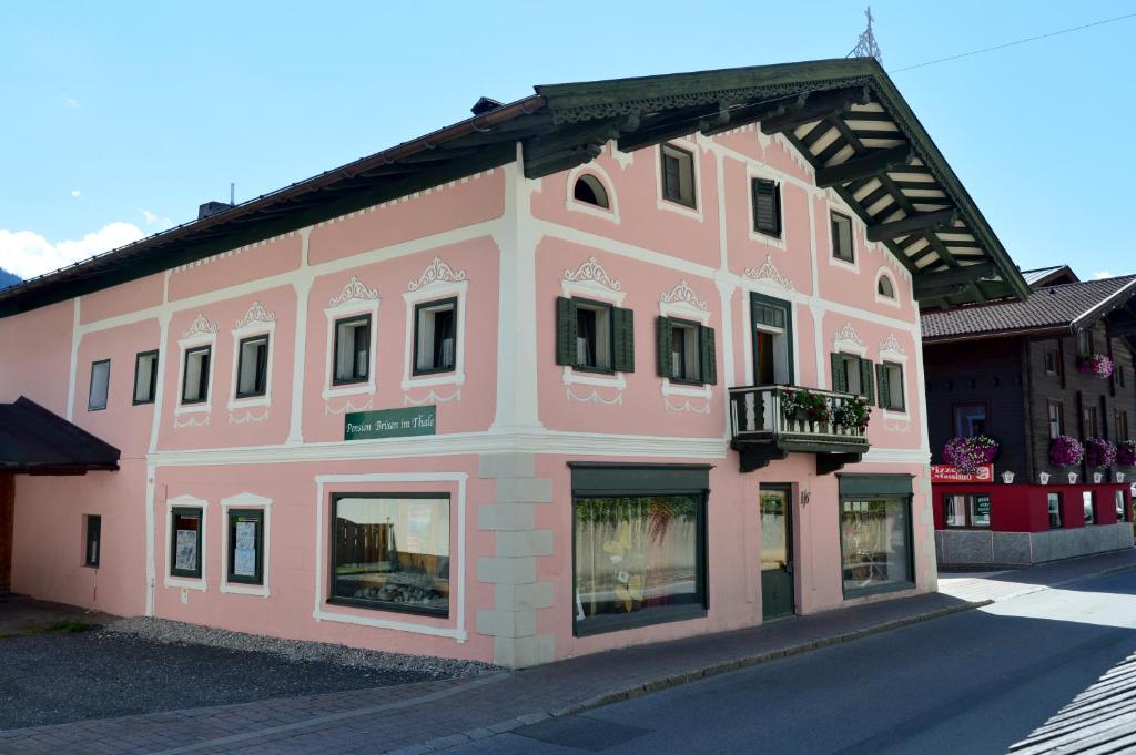 a pink building with a balcony on a street at Pension Brixen im Thale in Brixen im Thale
