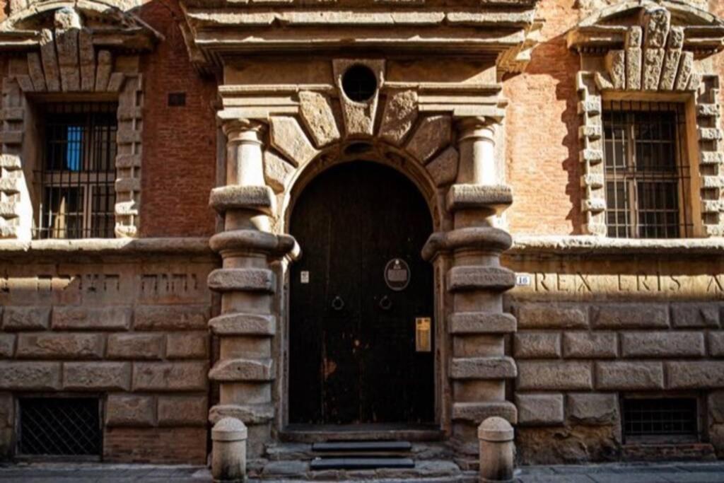 a brick building with a black door with an arch at Appartamento Palazzo Bocchi in Bologna