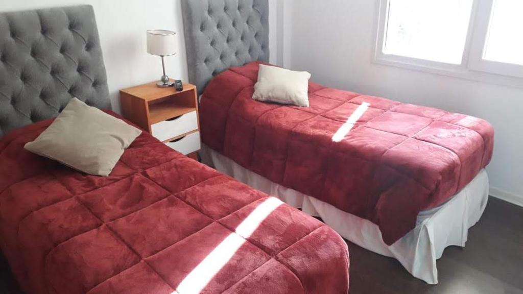 a bedroom with two beds with red covers and a window at Departamento Centrico en Bariloche Iß in San Carlos de Bariloche
