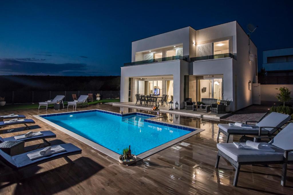 eine Villa mit einem Pool in der Nacht in der Unterkunft Villas Royal II with Private Pool in Novalja