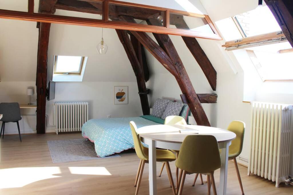 een slaapkamer met een bed en een tafel en stoelen bij Cocon plein centre ville - parking privé in Auxerre