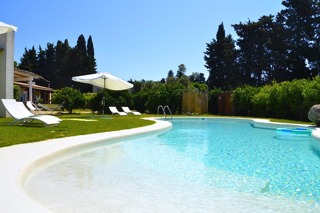 a swimming pool with chairs and an umbrella at Luna&Limoni Country in Muravera