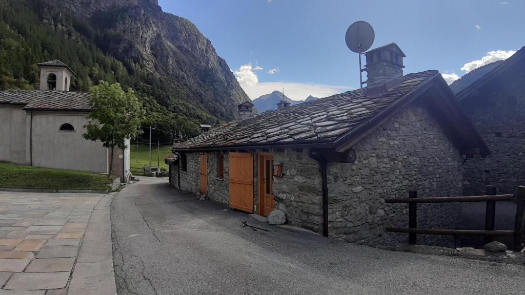 un piccolo edificio in pietra con una chiesa in montagna di Maisonnette de montagne a Ollomont