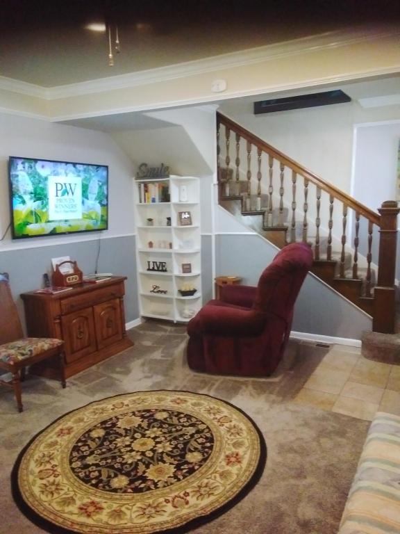 uma sala de estar com uma televisão, uma cadeira e um tapete em 3-Br 2-Bath Family-Friendly Home -10 Min to Tulsa em Tulsa