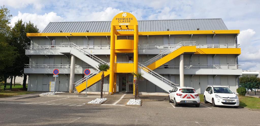 a yellow building with a car parked in front of it at Premiere Classe Agen in Agen