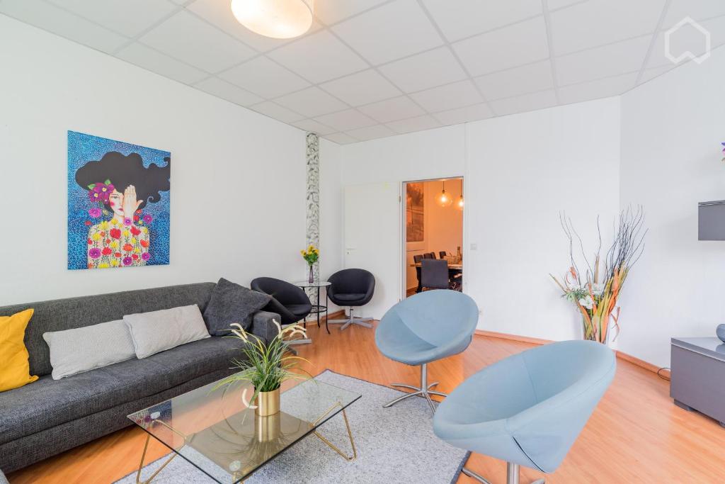 ベルリンにあるSpacious and modern furnished apartment for 10 guestsのリビングルーム(グレーのソファ、青い椅子付)