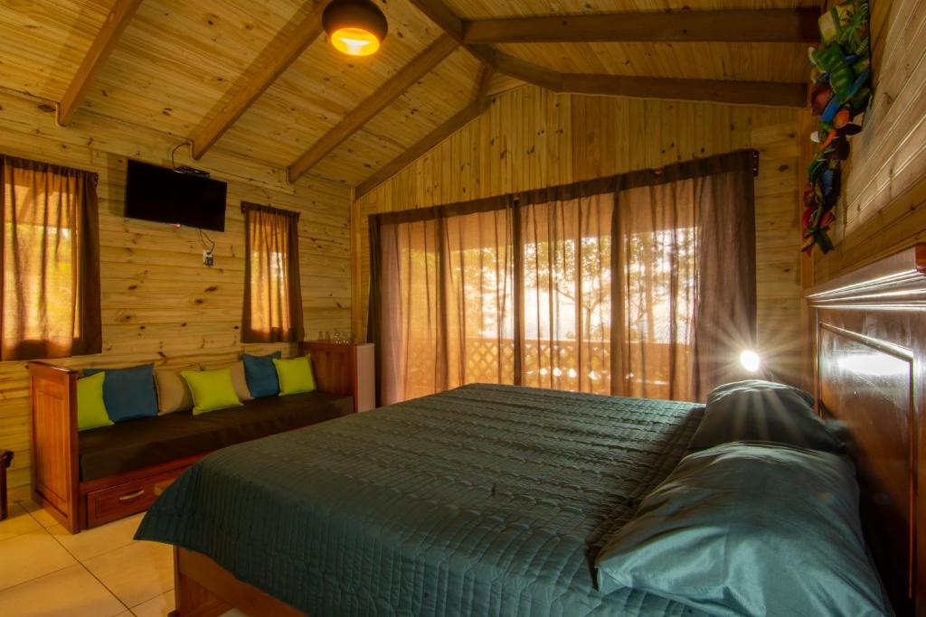 ein Schlafzimmer mit einem Bett in einer Holzhütte in der Unterkunft Mirador Valle del General in La Ese