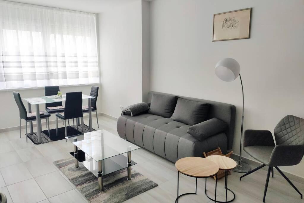 sala de estar con sofá, mesa y sillas en Pláza Apartman - city center, free parking, free wifi en Debrecen