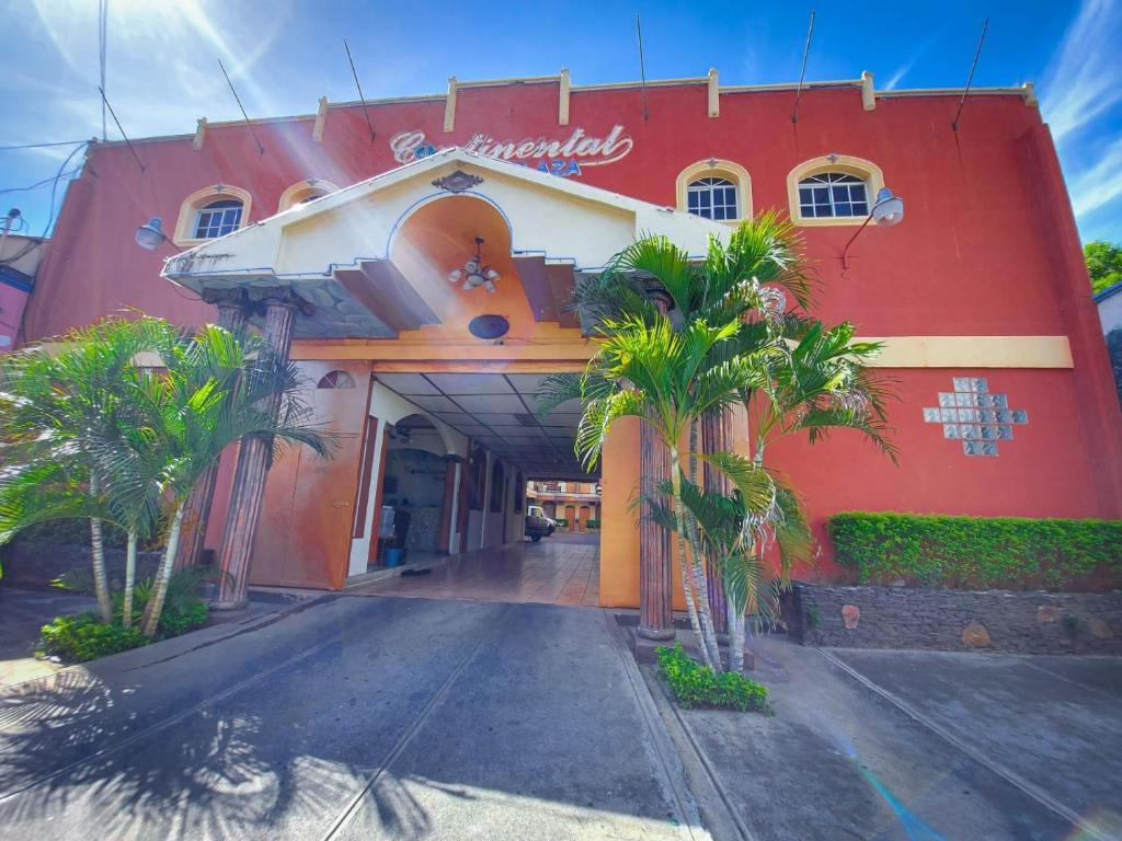 un edificio rojo con palmeras delante en Hotel Continental Plaza, en San Miguel
