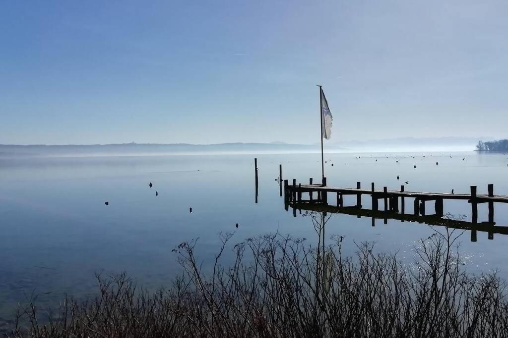 un muelle con una bandera en medio de un lago en FeWo Happy Place in traumhafter Lage See nah, en Utting am Ammersee