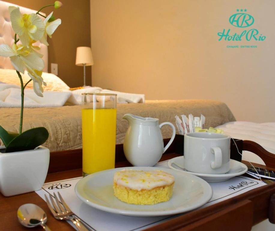 a table with a plate with a doughnut and a glass of orange juice at Hotel Río in Chajarí