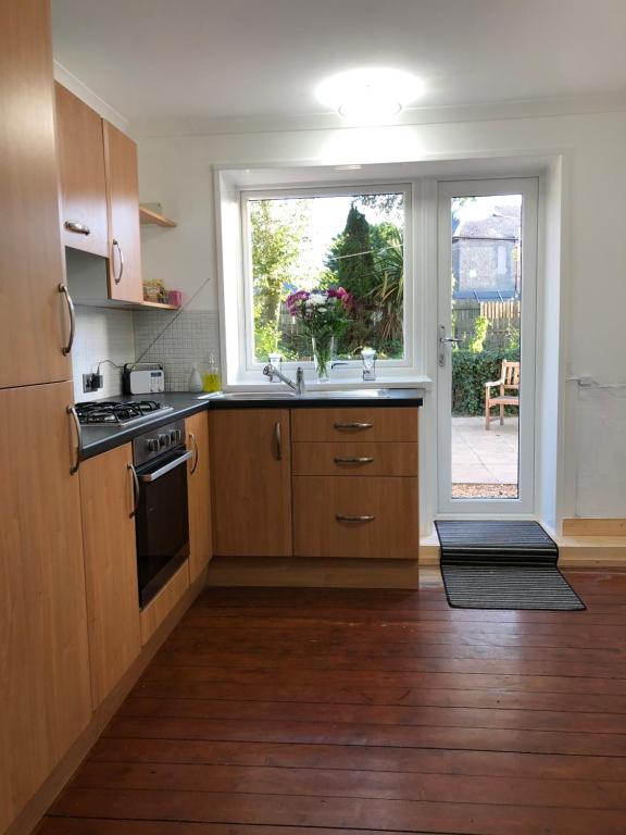 a kitchen with wooden cabinets and a window and a sink at ACE Largs Ground Floor Apartment with Garden in Largs