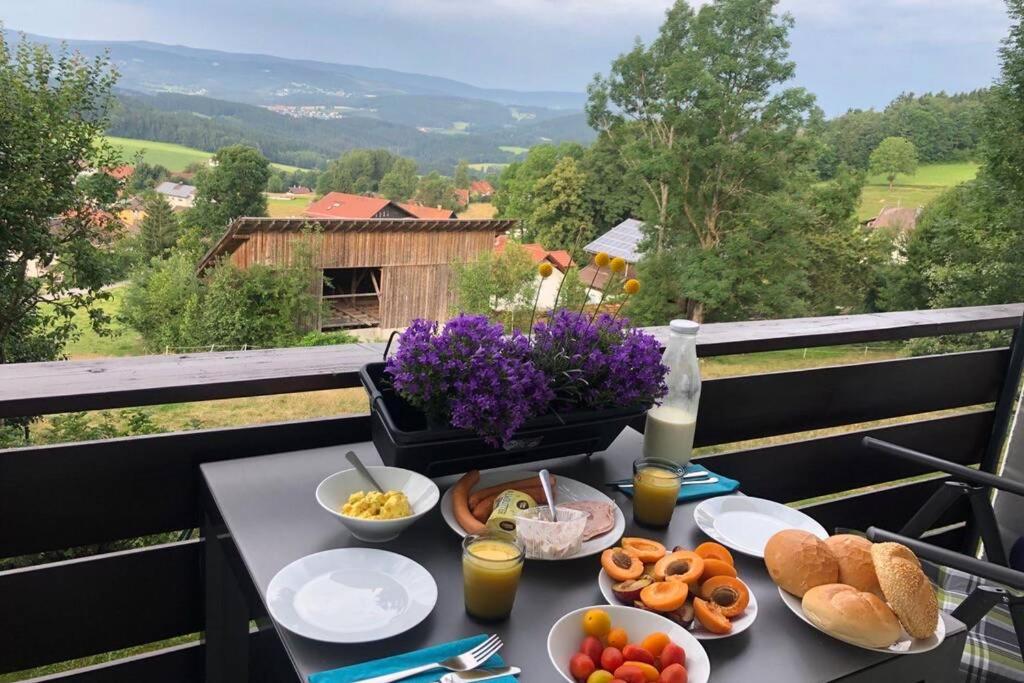 a table with breakfast food on a balcony at Apartment Panoramablick in Böbrach