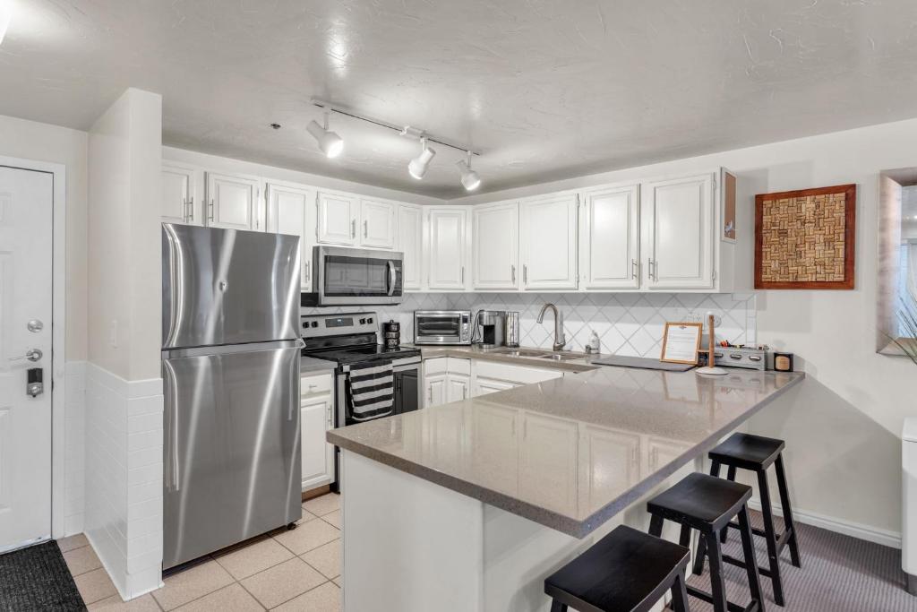a kitchen with white cabinets and a stainless steel refrigerator at 2BD 2BA Condo with Hot Tub and Pool in Park City
