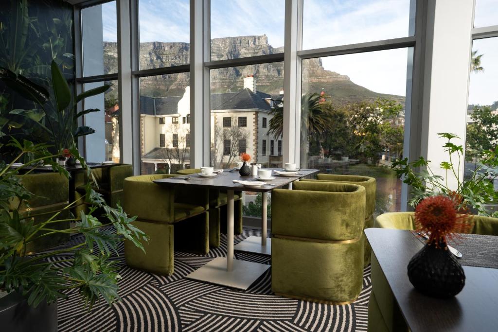 stół i krzesła w pokoju z widokiem na góry w obiekcie The Capital 15 on Orange Hotel & Spa w Kapsztadzie