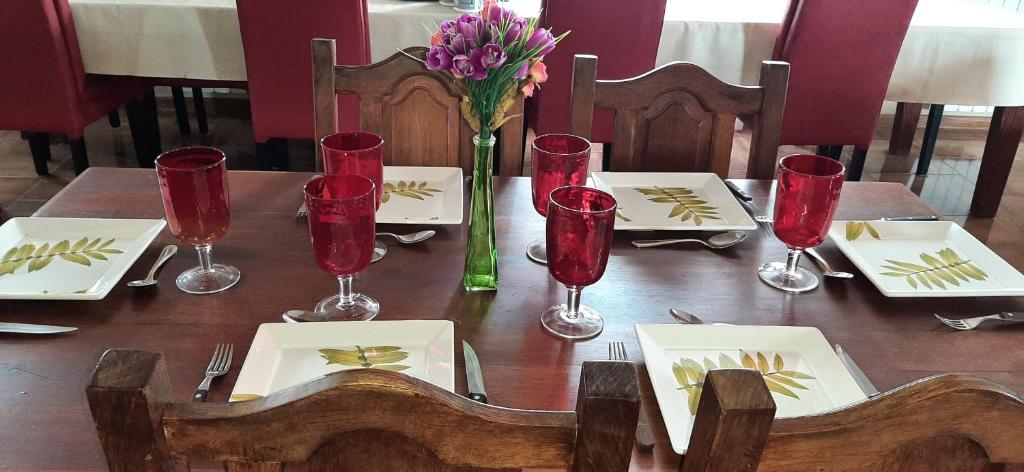 a wooden table with red glasses and a vase of flowers at SHOTEL Calafate in El Calafate