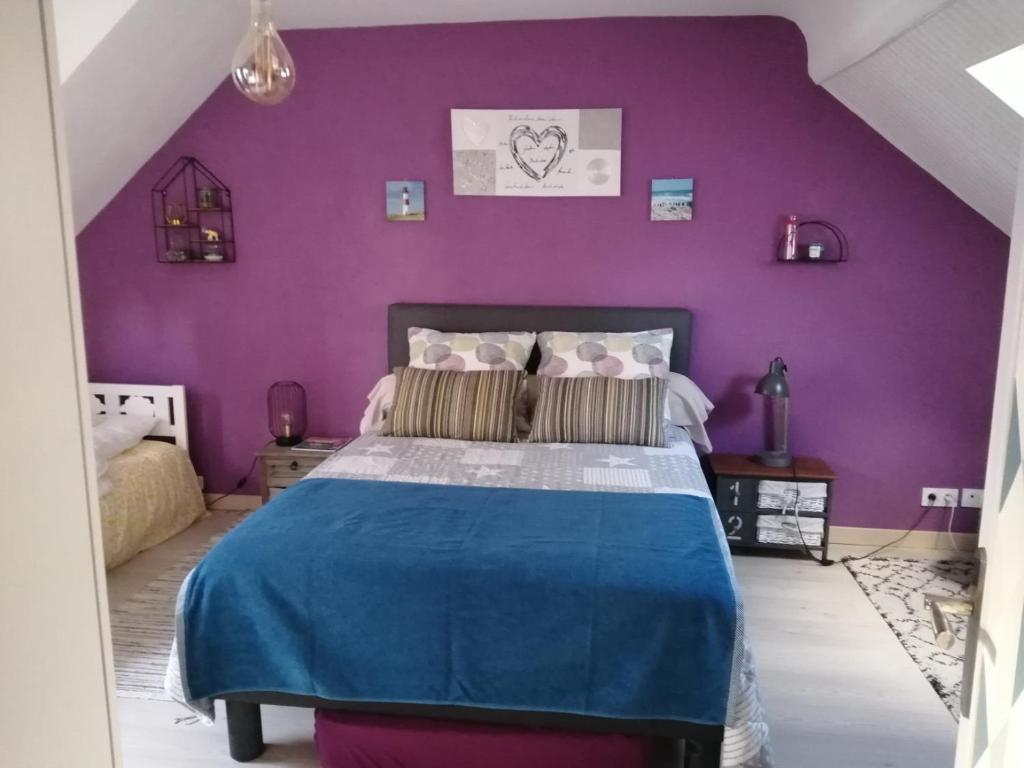 - une chambre avec un mur violet et un lit dans l'établissement GINGER, à Cancale