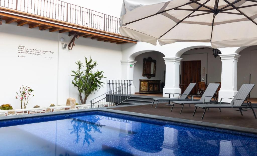 a pool in a house with chairs and an umbrella at Hotel Boutique Naura Centro in Oaxaca City