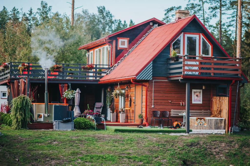 uma cabana de madeira com um telhado vermelho em Resort "Lavenders Dream SPA" em Vangaži