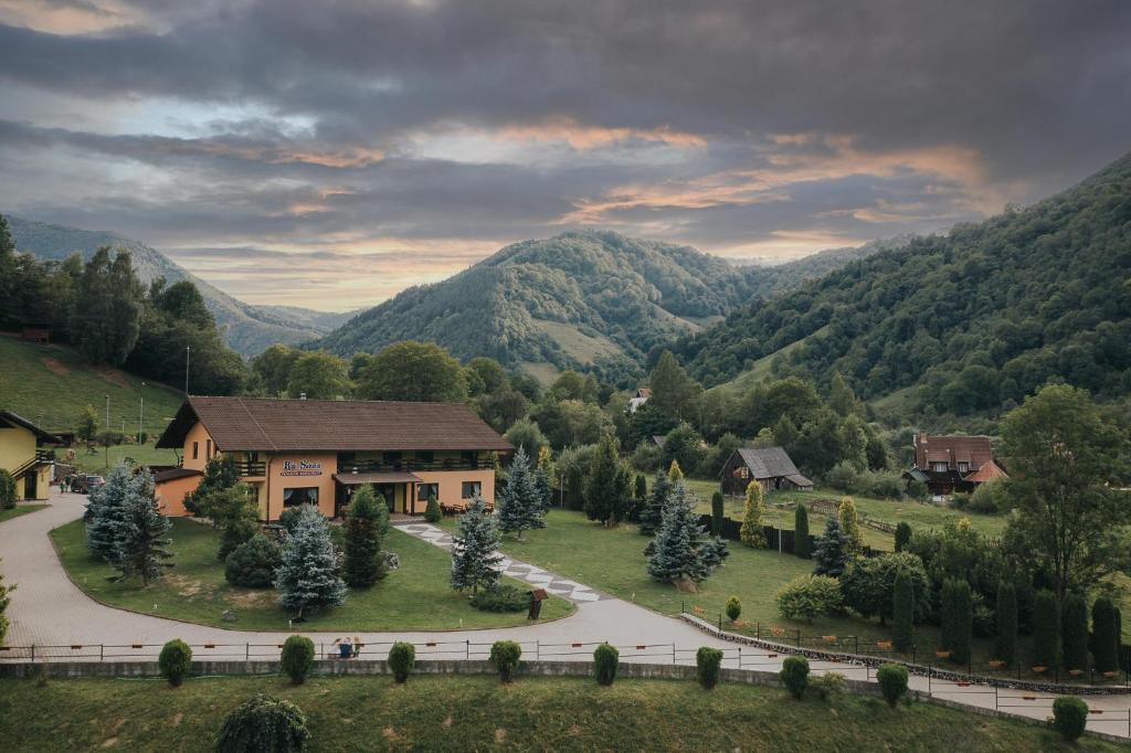 une maison dans une vallée avec des montagnes en arrière-plan dans l'établissement Pensiunea Rau Sadului, à Rau Sadului