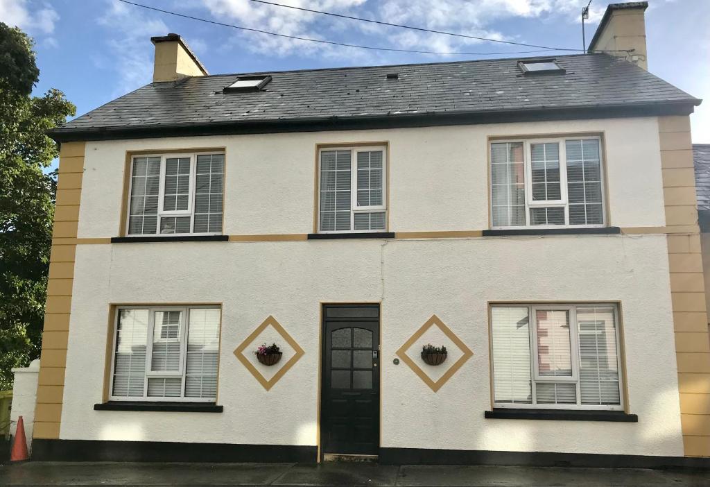 Casa blanca con puerta y ventanas negras en The Strand Guest House, en Falcarragh
