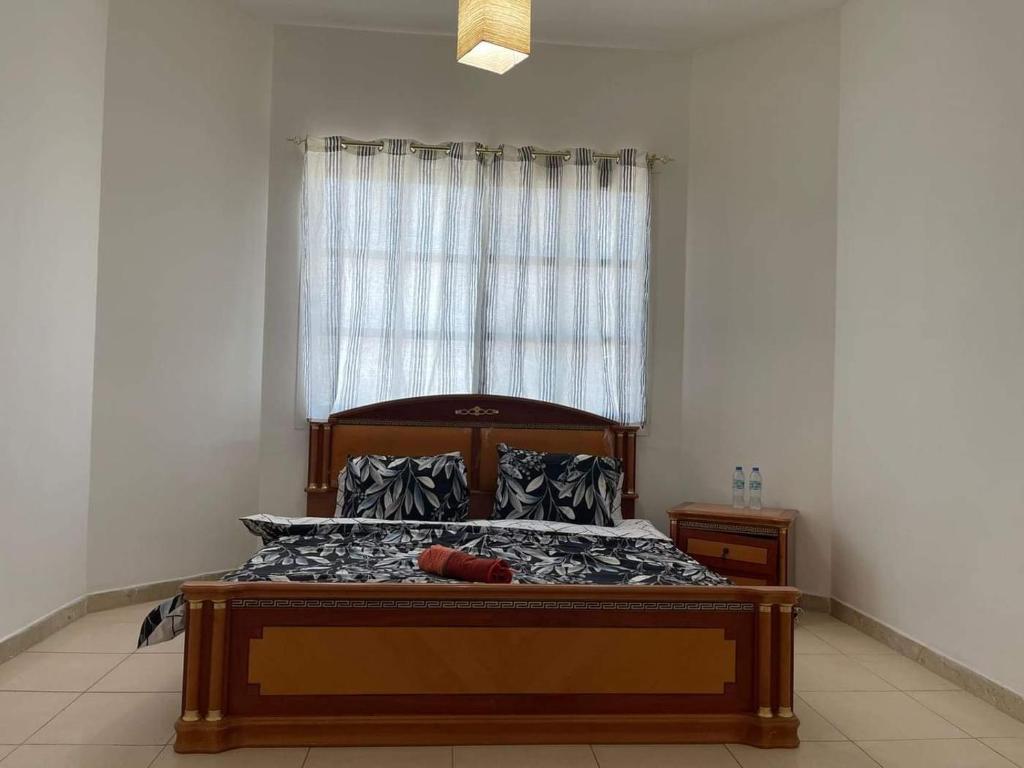 a bedroom with a wooden bed with a window at Furnished room in a villa in town center. With private bathroom in Al 'Ayn