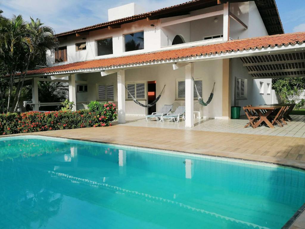 a villa with a swimming pool in front of a house at Villa Oloh com lazer completo em Caucaia - CE in Caucaia