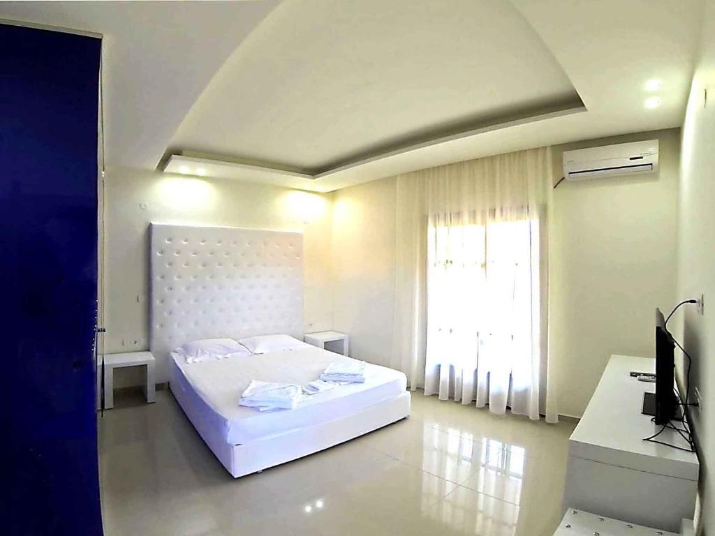 a white bedroom with a bed and a window at Macedon in Limenas