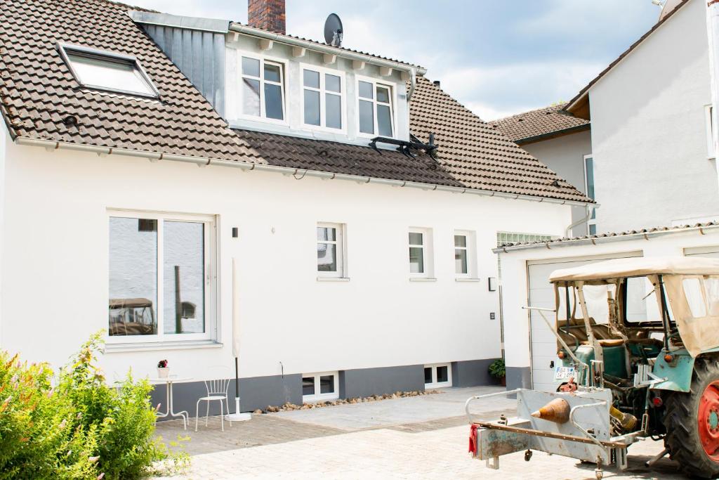 una casa blanca con un tractor estacionado frente a ella en Ferienwohnung auf ehemaligen Bauernhof in der Nähe von Bamberg, en Walsdorf