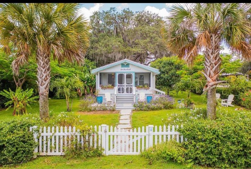 una pequeña casa con una valla blanca y palmeras en Charming 1935 Florida Cottage overlooking Lake Tulane, en Avon Park