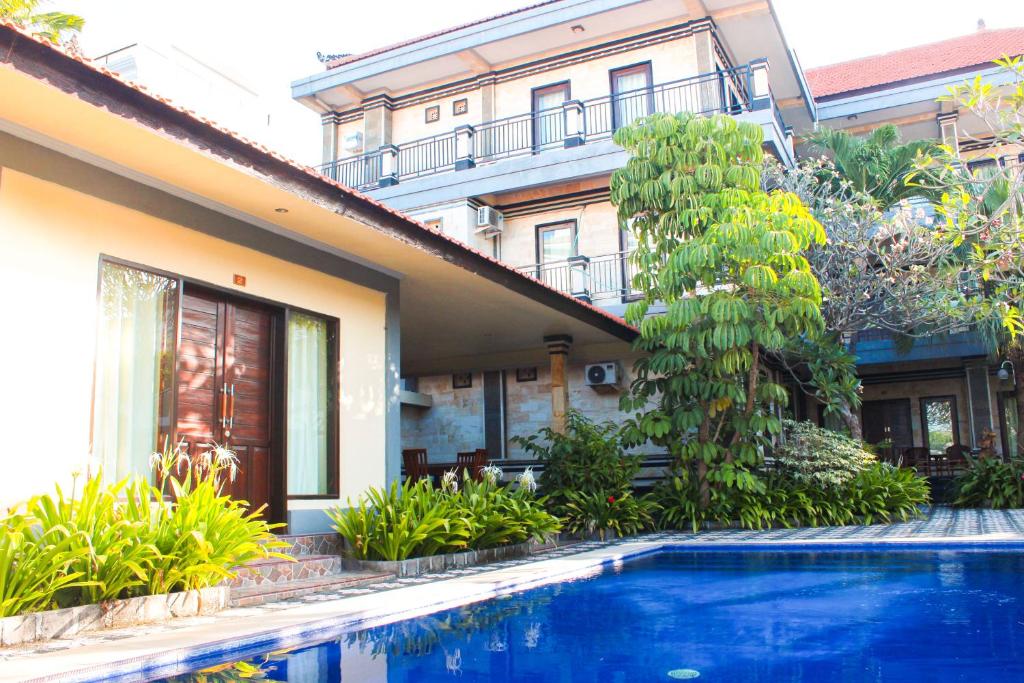 a house with a swimming pool in front of a building at Putu Guest House 2 in Canggu