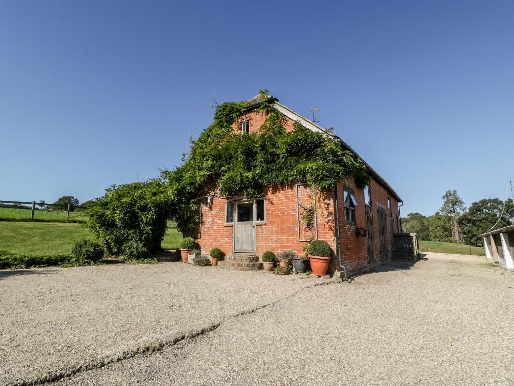 a brick building with ivy growing on the side of it at Breaches Barn in Rockbourne